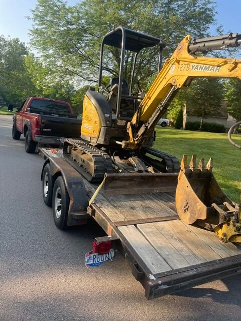 Red Truck with Trailer carrying yellow excavation tool. Cincinnati Ohio